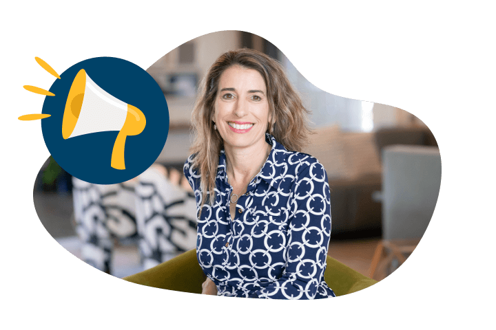 Franchise_Culture_5050_1 Smiling woman with shoulder-length hair in a patterned blouse, sitting indoors with a blurred background, embodies the entrepreneurial spirit of a Unishippers franchise. A graphic of a megaphone is overlaid on the left side.