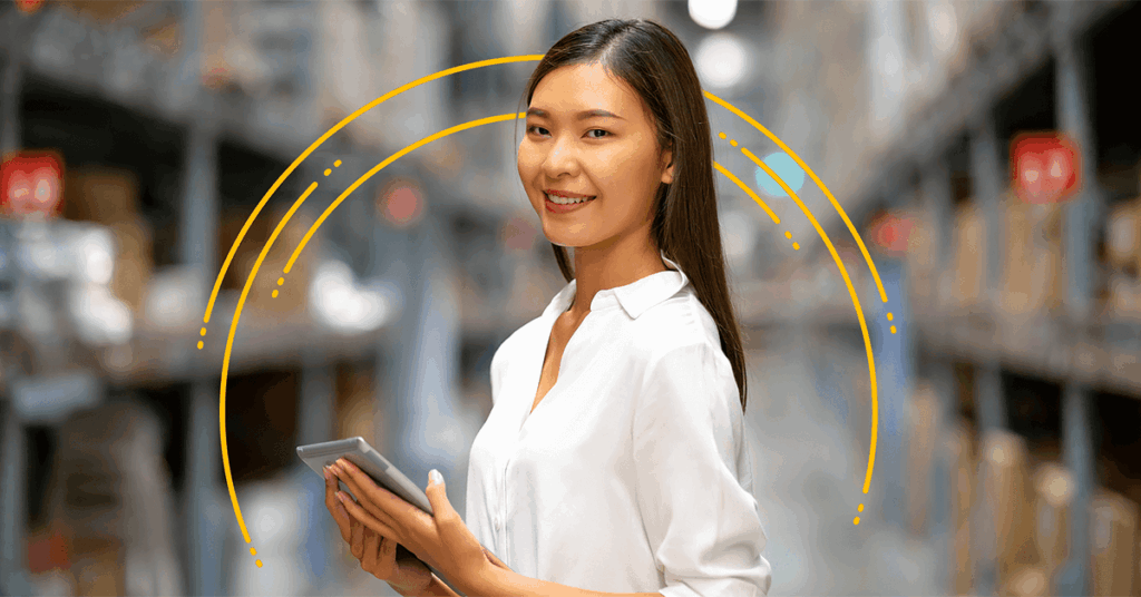 A woman in a white blouse stands in a warehouse aisle, smiling at the camera and holding a digital tablet, with yellow curved lines illustrated behind her. Shelves with boxes are visible in the background.