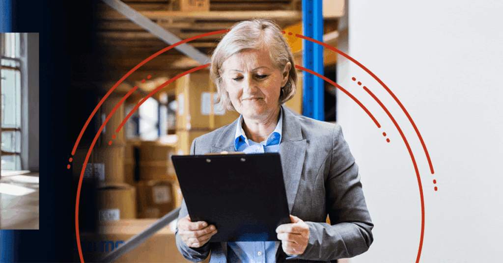 A woman with short blonde hair in a blazer stands in a warehouse, smiling while holding a clipboard. Cardboard boxes are stacked in the background. Red graphic circles are overlaid on the image.