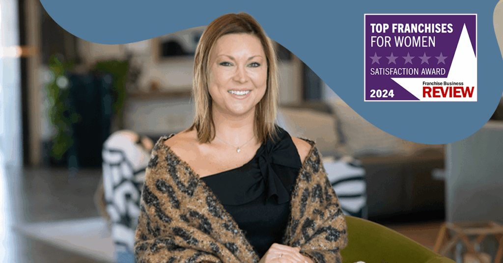 A smiling woman sits indoors wearing a patterned shawl. In the top right corner, a badge reads Top Franchises for Women 2024 Satisfaction Award, Franchise Business Review.