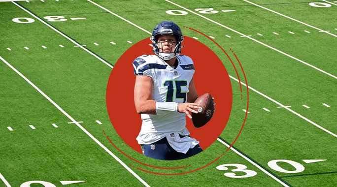 A football player in a Seattle Seahawks uniform holds a football, preparing to throw. He is centered in a red circle overlay, set against the green field—embodying the drive and teamwork found at every Unishippers Franchise.