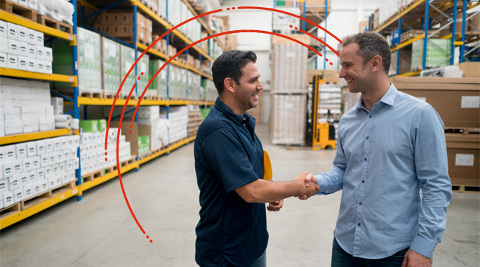 Two men smiling and shaking hands in a warehouse aisle lined with shelves of boxes, highlighting shipping franchise opportunities; red curved lines are digitally added above and behind them.